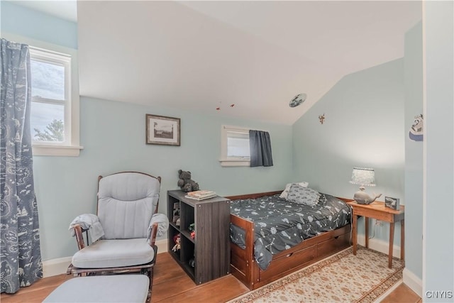 bedroom with baseboards, vaulted ceiling, and wood finished floors