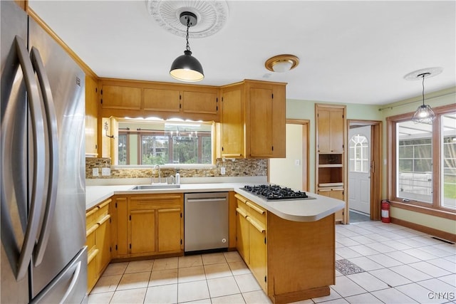 kitchen with decorative backsplash, appliances with stainless steel finishes, a sink, light countertops, and a peninsula