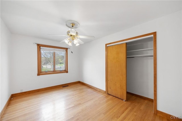 unfurnished bedroom featuring light wood-style floors, baseboards, ceiling fan, and a closet