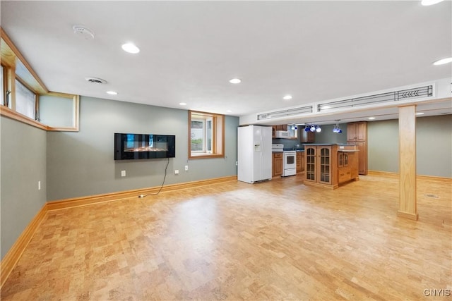 below grade area featuring white refrigerator with ice dispenser, recessed lighting, baseboards, light wood-type flooring, and bar area
