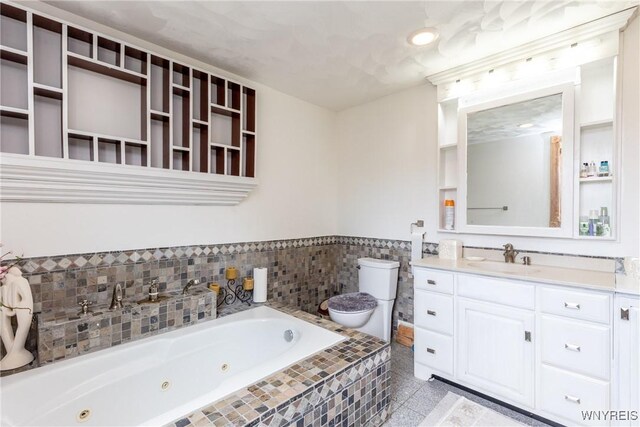 bathroom featuring vanity, toilet, a jetted tub, recessed lighting, and a wainscoted wall