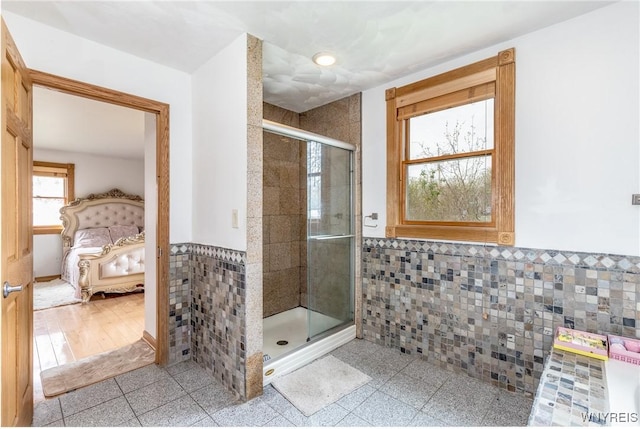 ensuite bathroom with a wainscoted wall, recessed lighting, tile walls, a shower stall, and ensuite bathroom