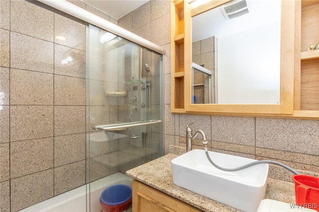 bathroom featuring decorative backsplash, visible vents, vanity, toilet, and enclosed tub / shower combo