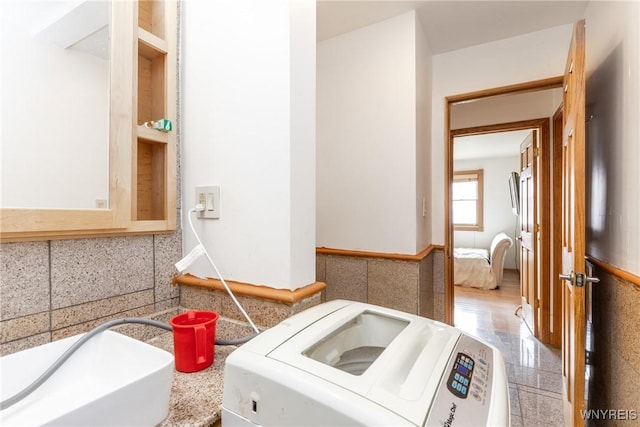bathroom featuring washer / dryer, granite finish floor, and tile walls