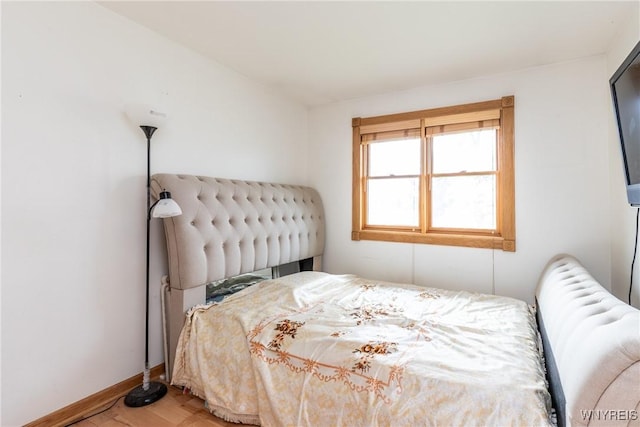 bedroom featuring baseboards, radiator heating unit, and wood finished floors