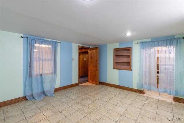 unfurnished room with baseboards and built in features