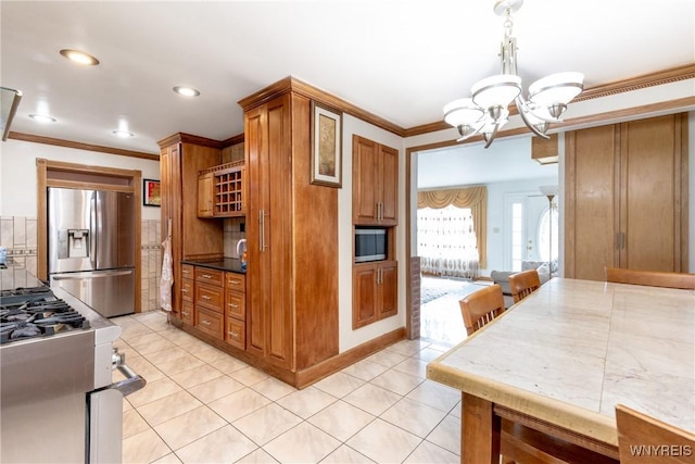 kitchen featuring brown cabinetry, crown molding, appliances with stainless steel finishes, and an inviting chandelier