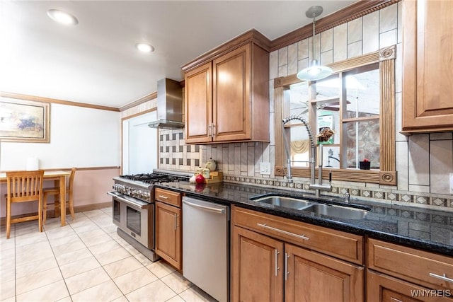 kitchen featuring wall chimney range hood, backsplash, appliances with stainless steel finishes, and a sink