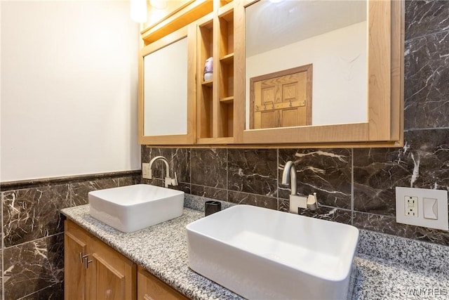 full bathroom featuring a sink, tile walls, and double vanity