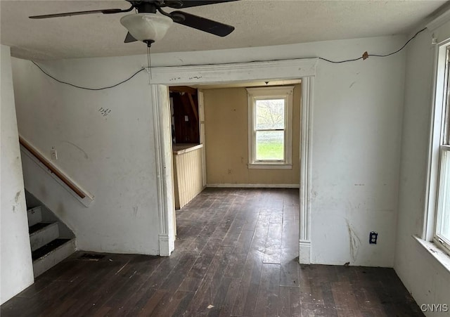 unfurnished room featuring stairs, a ceiling fan, and dark wood-style floors