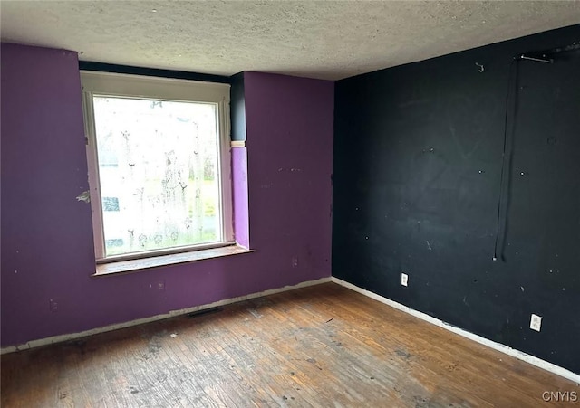 unfurnished room featuring a textured ceiling, baseboards, and hardwood / wood-style flooring