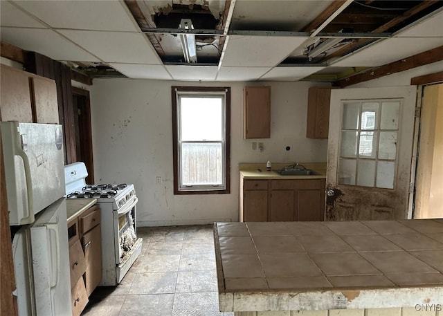 kitchen featuring tile counters, a sink, and white appliances