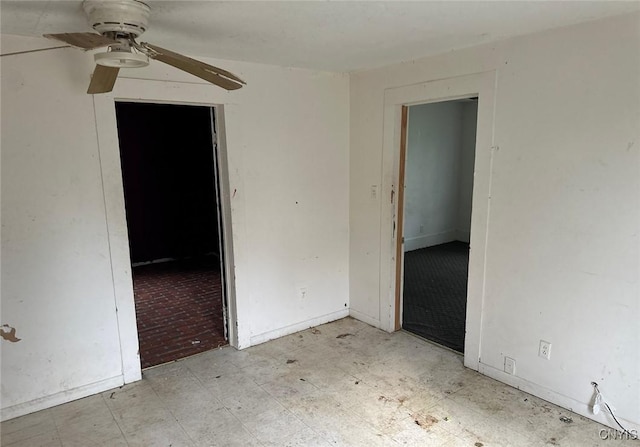 empty room featuring a ceiling fan, tile patterned floors, and baseboards