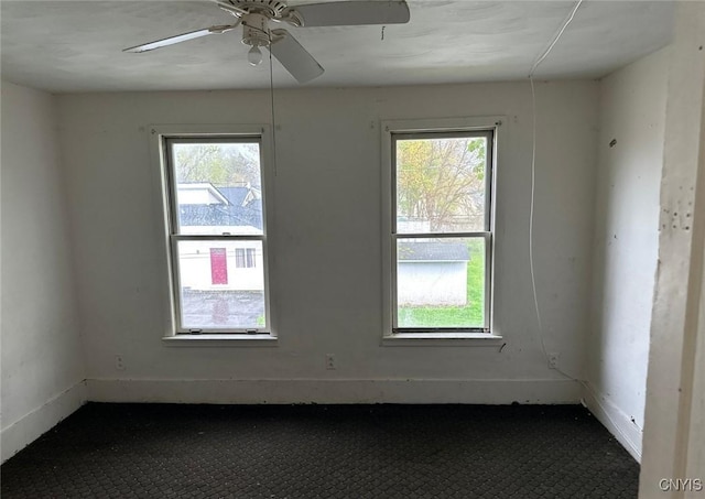 unfurnished room featuring plenty of natural light, a ceiling fan, and baseboards