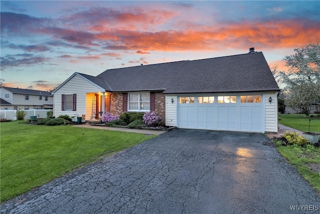 view of front facade featuring fence, an attached garage, a front yard, and aphalt driveway