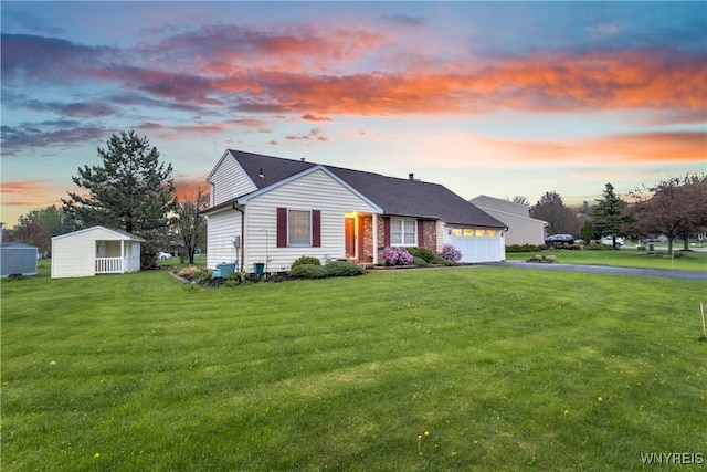 view of front of home featuring a storage shed, an attached garage, driveway, and a front yard