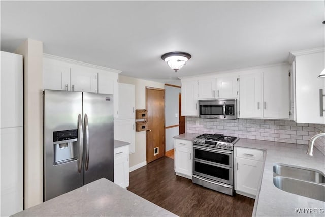 kitchen with dark wood-type flooring, a sink, white cabinets, and stainless steel appliances