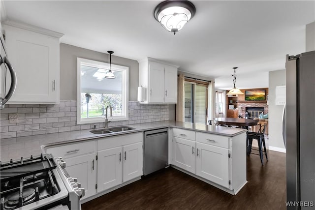 kitchen featuring dark wood finished floors, a sink, white cabinets, a peninsula, and stainless steel appliances