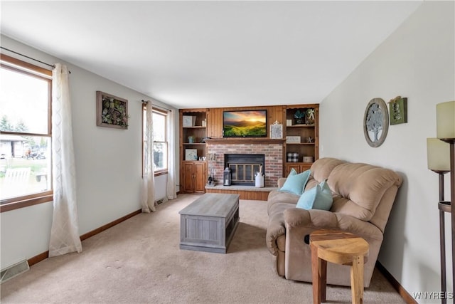living area with light colored carpet, a brick fireplace, built in shelves, baseboards, and visible vents
