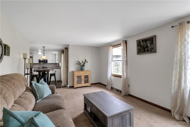 living room featuring baseboards, visible vents, and light carpet