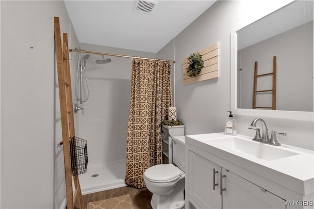 bathroom with vanity, toilet, wood finished floors, a shower with curtain, and visible vents