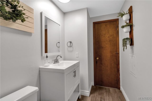 bathroom with vanity, baseboards, toilet, and wood finished floors