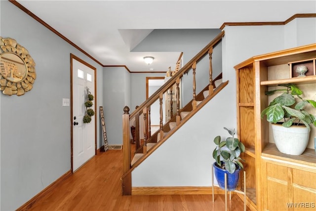 foyer entrance with stairway, baseboards, ornamental molding, and wood finished floors