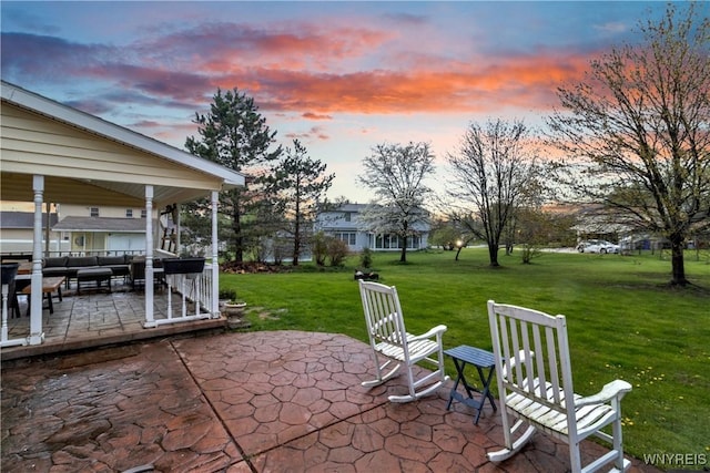 patio terrace at dusk featuring an outdoor living space and a lawn