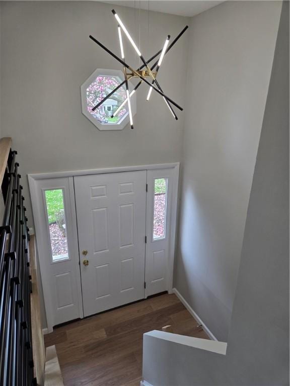 foyer entrance with an inviting chandelier, plenty of natural light, wood finished floors, and a towering ceiling