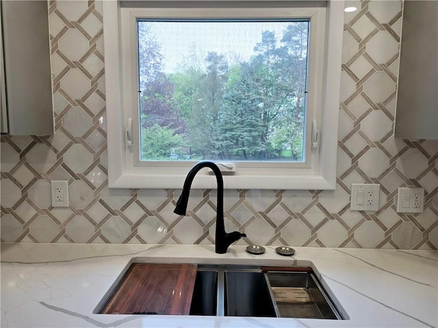 room details with light stone counters, a sink, and decorative backsplash