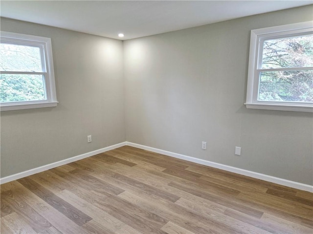 spare room with plenty of natural light, recessed lighting, light wood-style floors, and baseboards