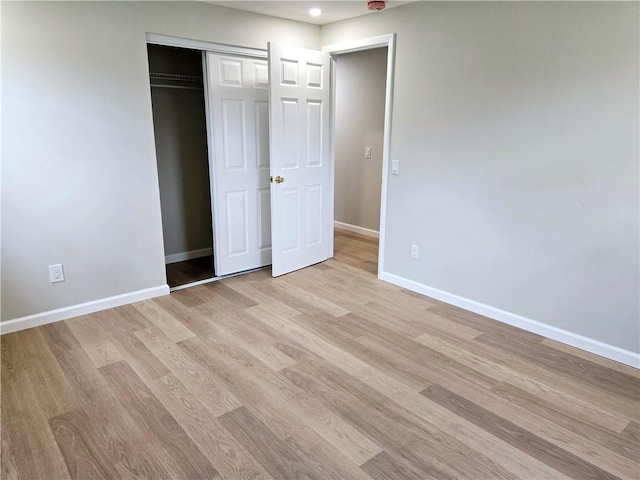 unfurnished bedroom with recessed lighting, baseboards, light wood-style flooring, and a closet