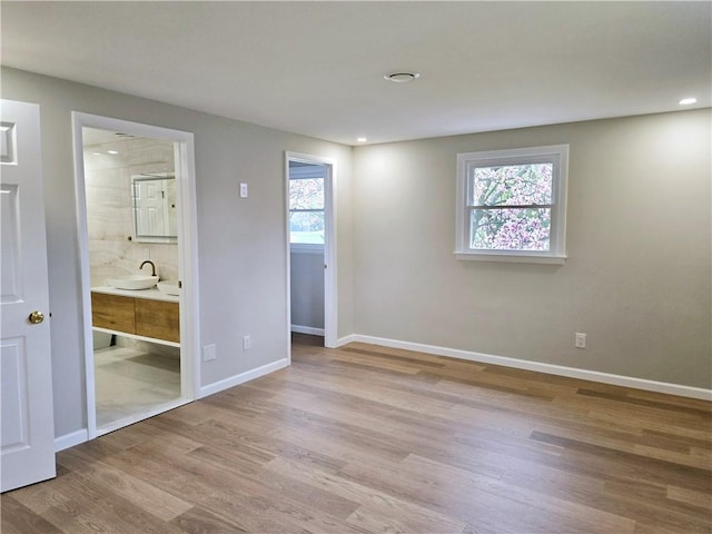 unfurnished bedroom featuring a sink, baseboards, recessed lighting, and wood finished floors