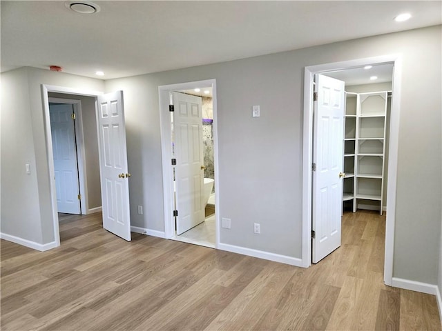 unfurnished bedroom featuring baseboards, recessed lighting, light wood-style flooring, and a spacious closet