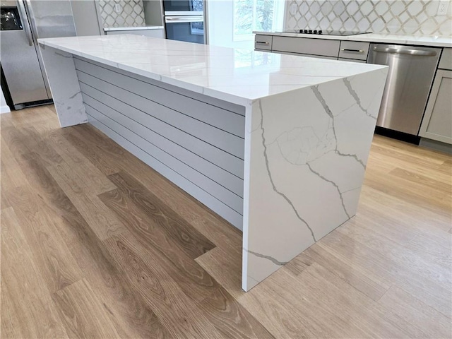 kitchen featuring gray cabinetry, appliances with stainless steel finishes, decorative backsplash, and light wood finished floors