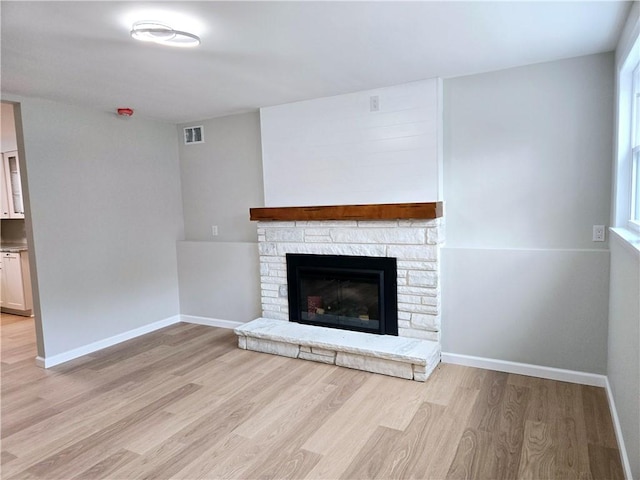unfurnished living room featuring light wood-style floors, baseboards, a fireplace, and visible vents
