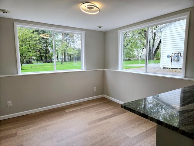unfurnished dining area featuring baseboards and wood finished floors
