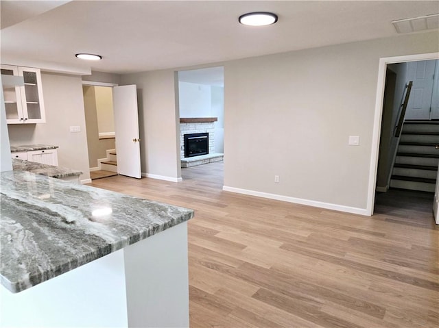 kitchen featuring white cabinets, light wood-style flooring, baseboards, visible vents, and glass insert cabinets