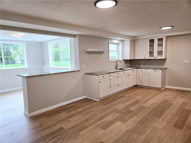 kitchen featuring baseboards, light wood finished floors, and light stone counters