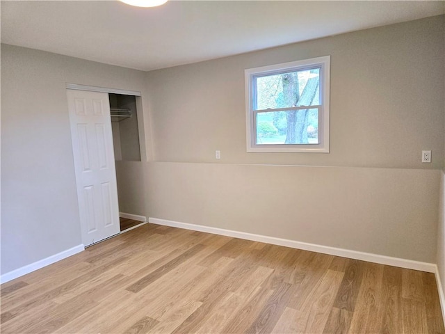 unfurnished bedroom featuring baseboards, a closet, and light wood finished floors