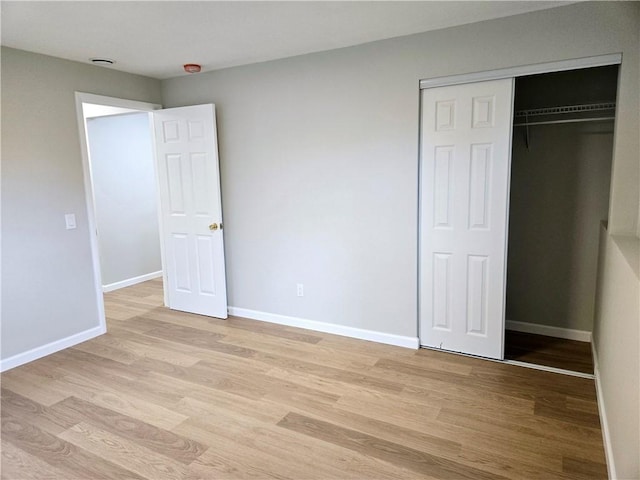 unfurnished bedroom with baseboards, light wood finished floors, and a closet