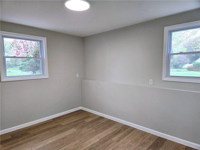 spare room featuring baseboards and wood finished floors