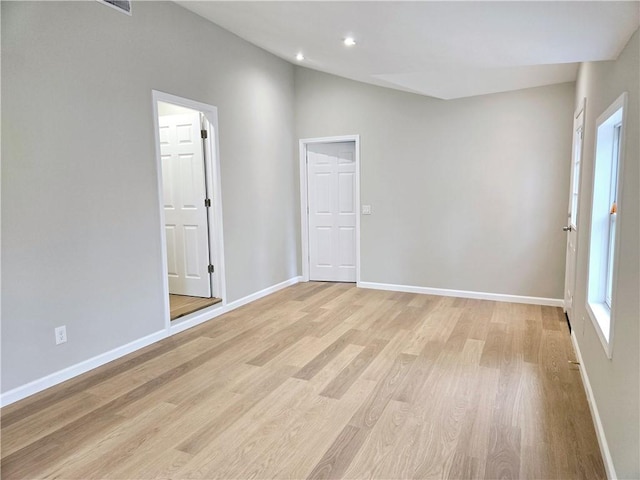 spare room with baseboards, recessed lighting, light wood finished floors, and lofted ceiling