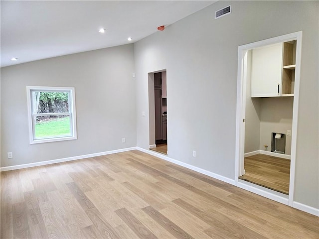 interior space with baseboards, lofted ceiling, light wood-style flooring, and visible vents