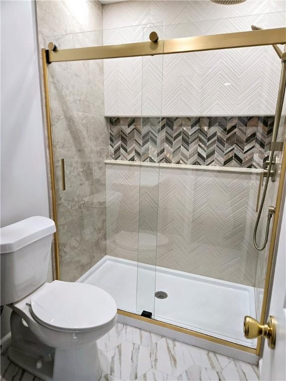 bathroom with a stall shower, toilet, and marble finish floor