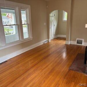 118 Ruhamah Ave, Onondaga, NY 13205 - unfurnished living room with arched walkways, baseboards, a healthy amount of sunlight, and light wood-style floors