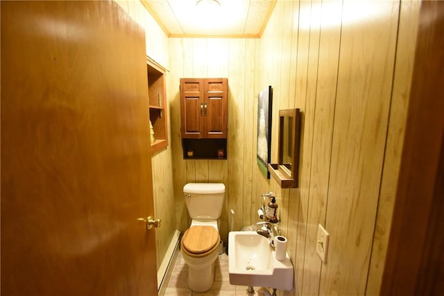 bathroom with a sink, wooden walls, baseboard heating, and toilet
