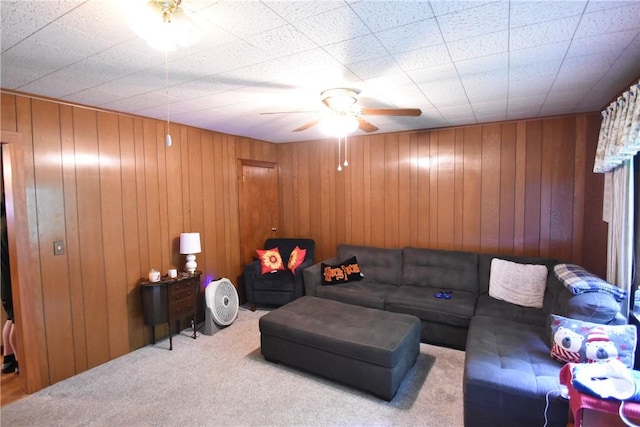 living room featuring carpet flooring, a ceiling fan, and wood walls