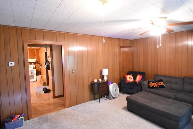 living room featuring carpet flooring, ceiling fan, and wood walls
