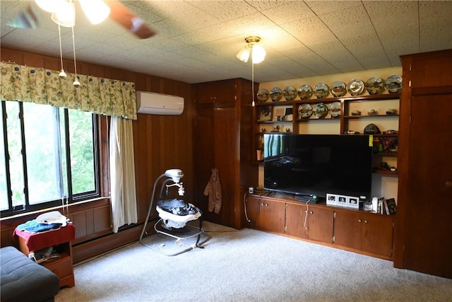 carpeted living area with an AC wall unit and ceiling fan